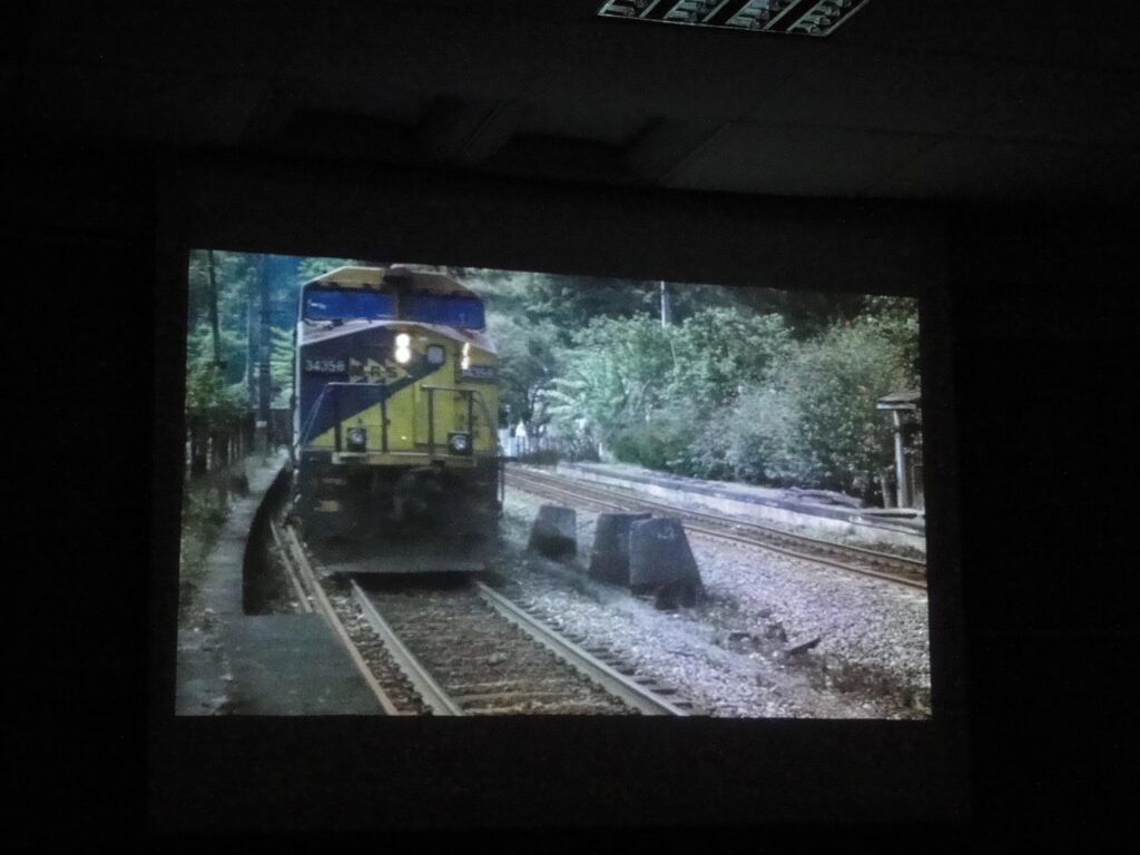 Foto da mostra do grupo Lugares, onde é visto um trem chegando